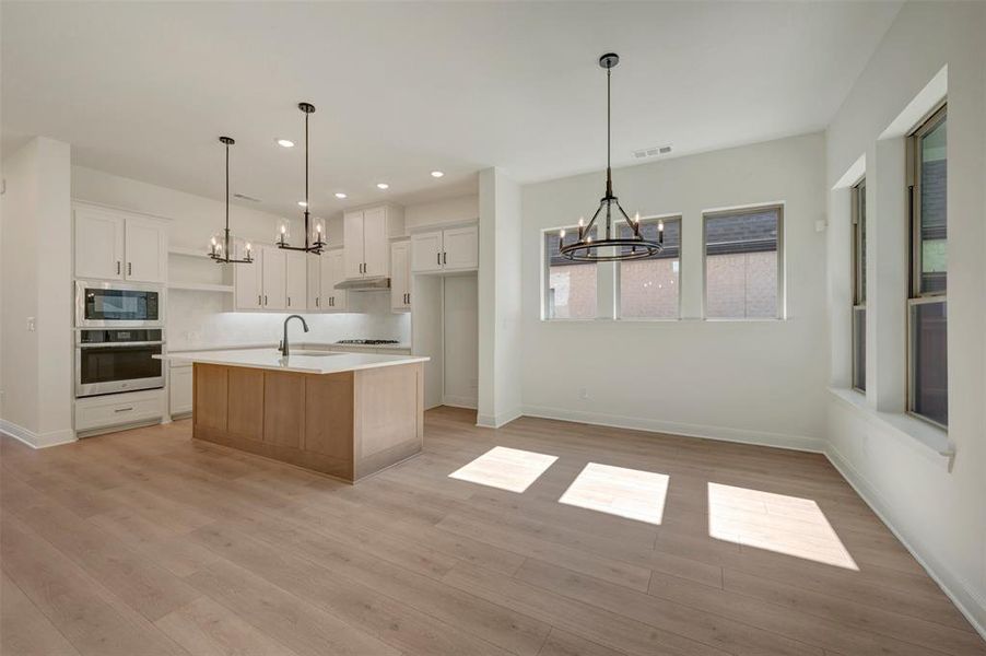 Open-concept kitchen and dining area featuring light wood-finish flooring Open-concept kitchen and dining area featuring light wood-finish flooring