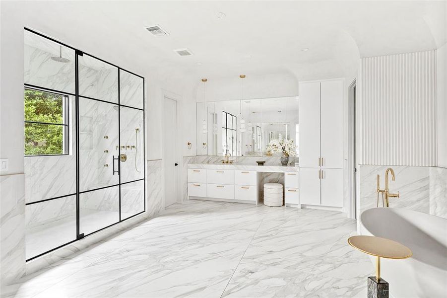 Enhancing the primary bathroom's unique elegance, is an exquisite cove ceiling adorned with stunning Venetian plaster walls. Large-format matte-finish porcelain tiles add an exquisite touch of sophistication and refinement to this incredible space. Separate sinks, vanities, and lavatories provide added convenience and discretion.