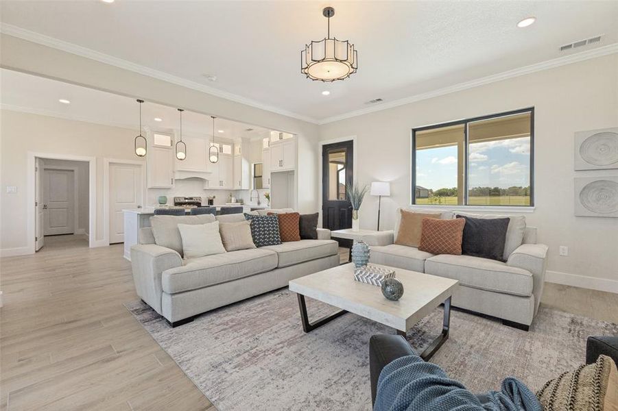 Open-concept living area featuring light wood-finish flooring, a contemporary chandelier, and recessed lighting
