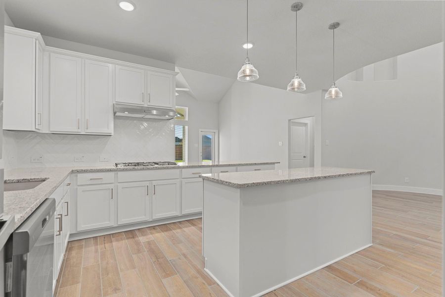 The chef-inspired kitchen shines with beautiful white shaker cabinets, gleaming granite countertops, and a large center island that provides plenty of workspace and casual seating—perfect for both family meals and entertaining guests.