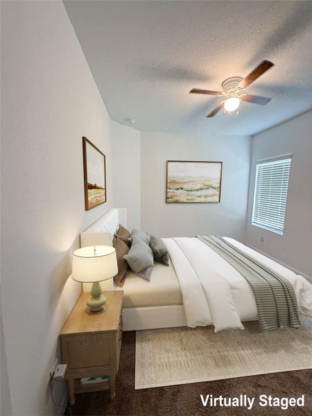 Comfortable bedroom features a ceiling fan, plush carpeting, and generous natural illumination.