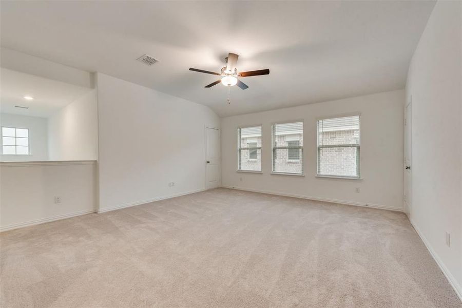 Empty room featuring ceiling fan, light carpet, and vaulted ceiling