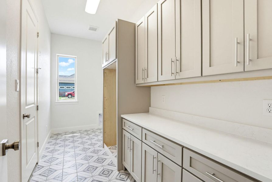 Functional utility room with ample storage cabinetry and durable countertops, ready for daily tasks.