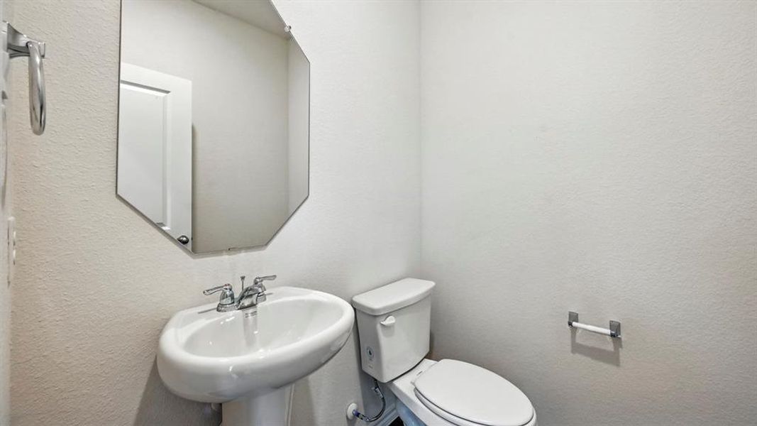 Pedestal sink with chrome fixtures and an octagonal mirror