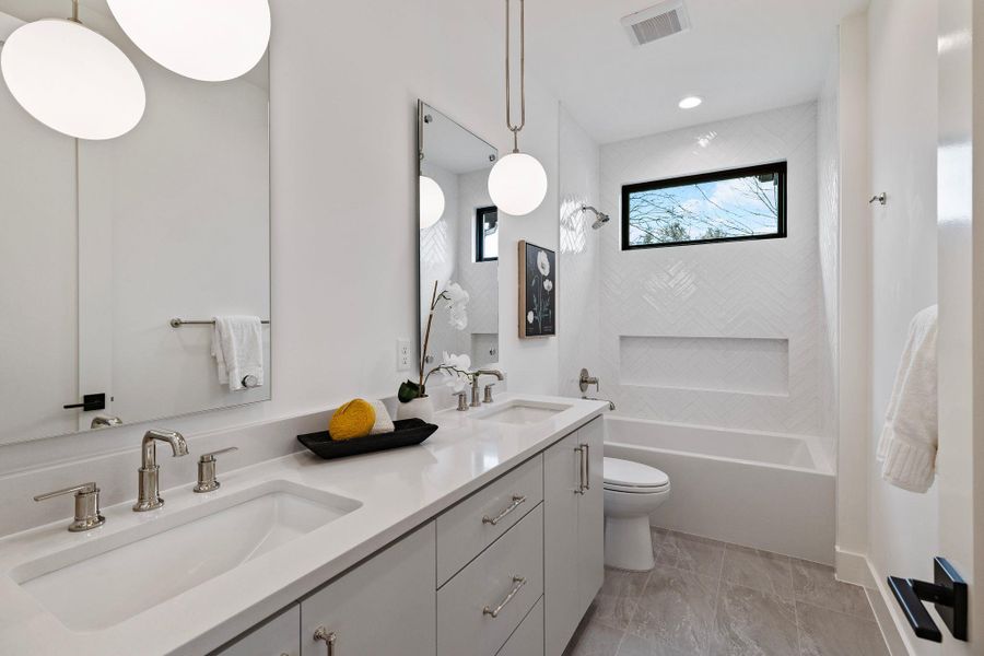 Bathroom featuring toilet, double vanity,  shower combination, marble finish floors, and recessed lighting