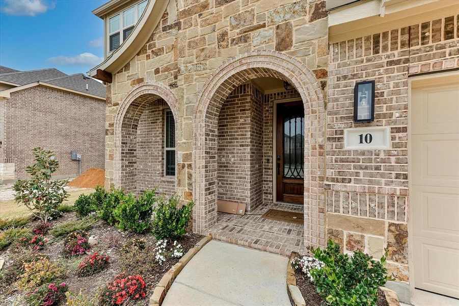 Welcoming entry with wood, iron and glass front door and landscaped yard Welcoming entry with wood, iron and glass front door and landscaped yard
