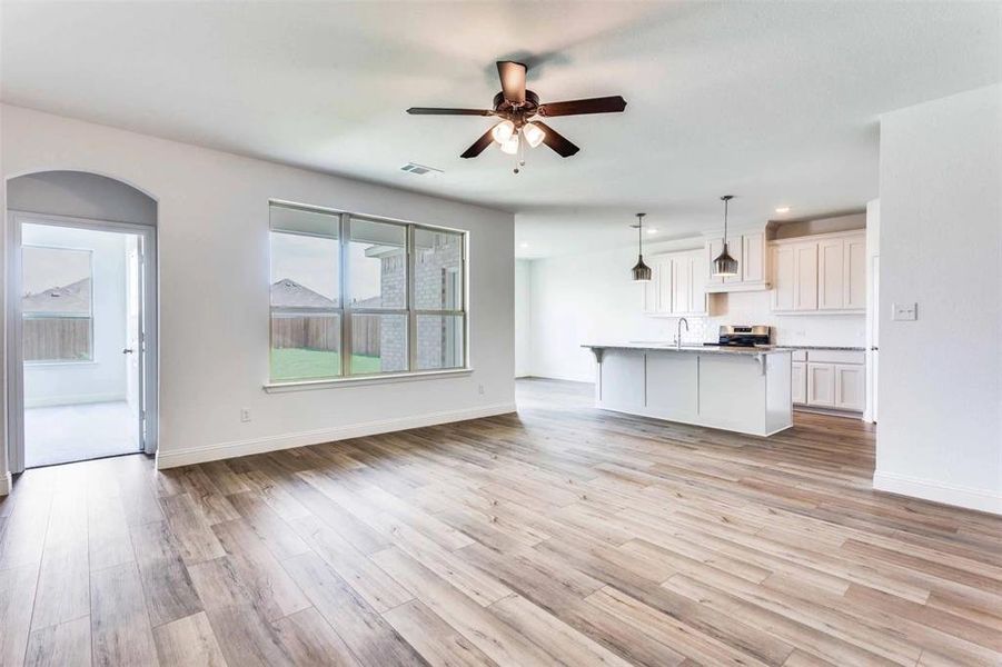 Unfurnished living room featuring ceiling fan, sink, and light hardwood / wood-style floors