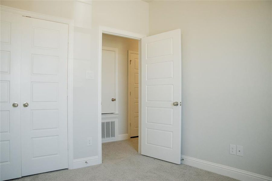 Unfurnished bedroom featuring light carpet and a closet