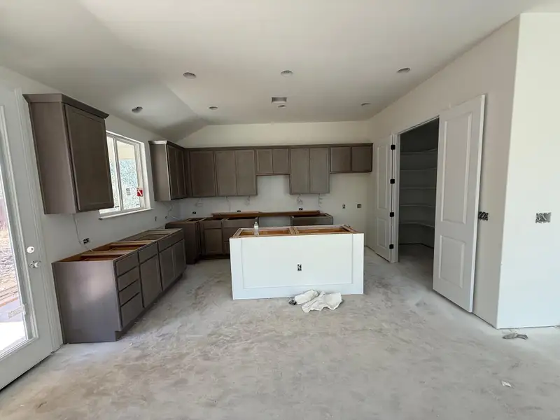 Kitchen with a kitchen island, vaulted ceiling, and dark brown cabinets