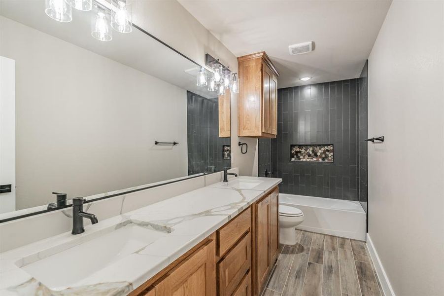Full bathroom with double vanity, shower combination, and wood finish floors Full bathroom with double vanity, shower combination, and wood finish floors