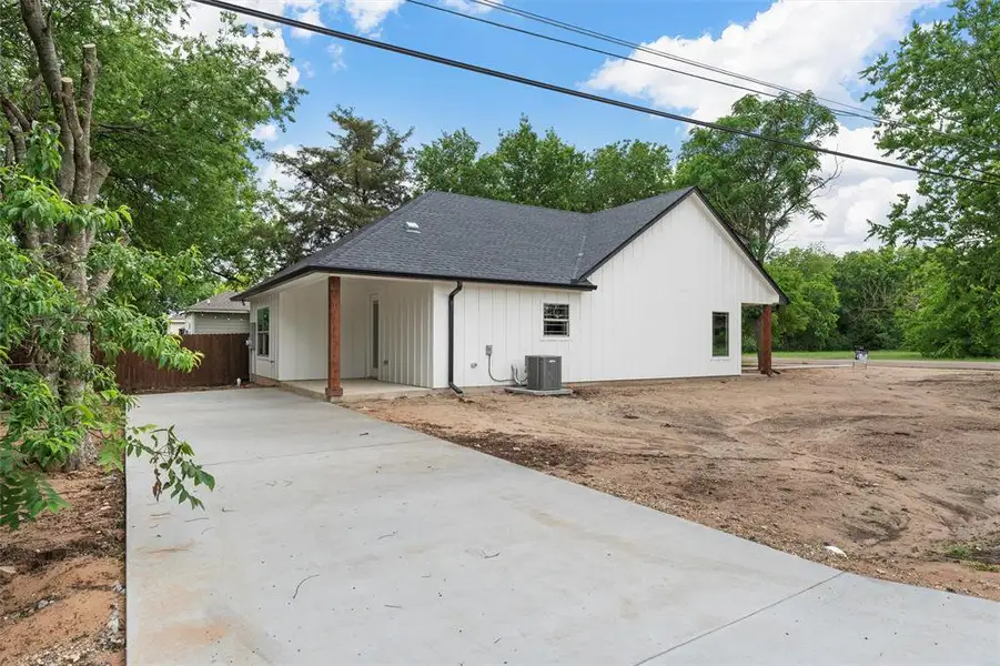 View of home's exterior featuring central AC unit, roof with shingles, concrete driveway, and fence