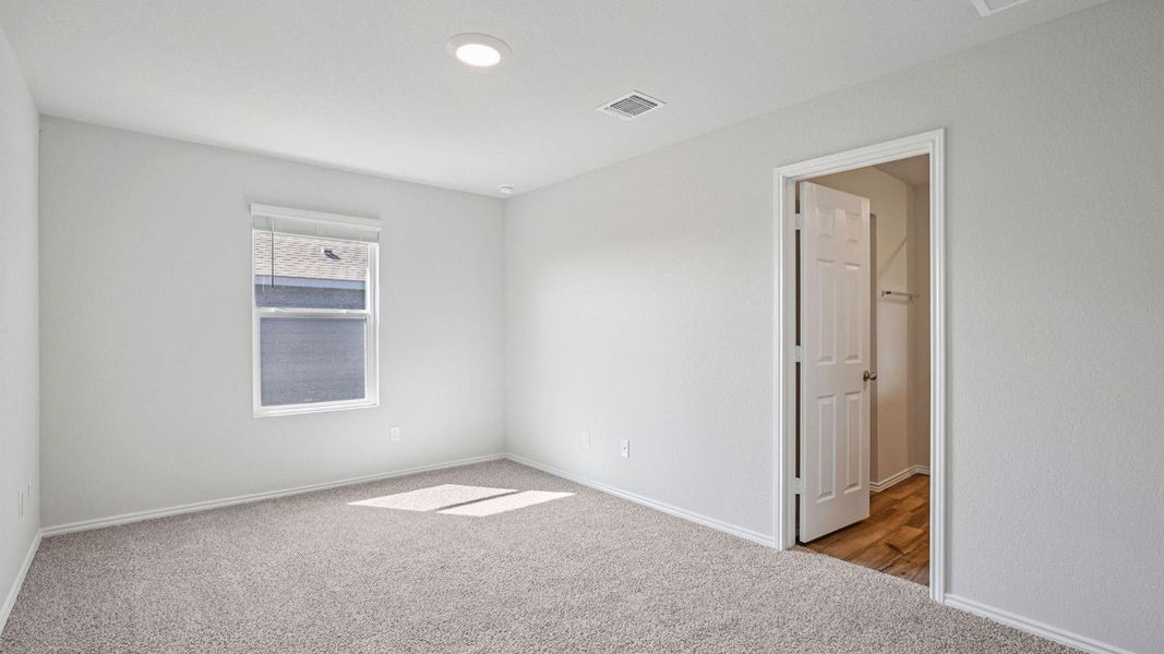 A well-lit bedroom with soft carpeting and natural light streaming through a window. A well-lit bedroom with soft carpeting and natural light streaming through a window.