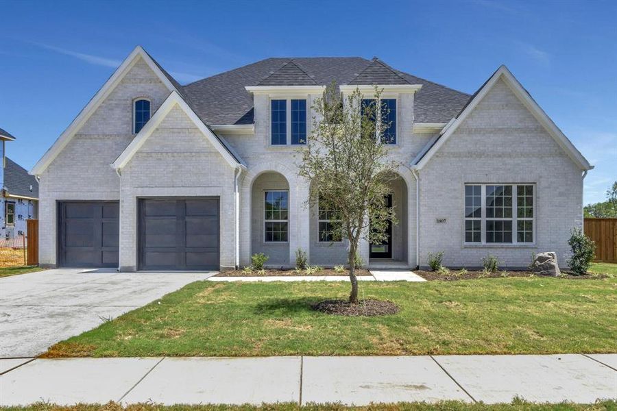 View of front facade featuring a garage and a front yard