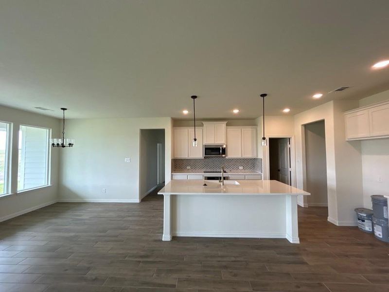 Open-concept kitchen and dining area featuring wood-finish flooring, recessed lighting, and a kitchen island with pendant lighting