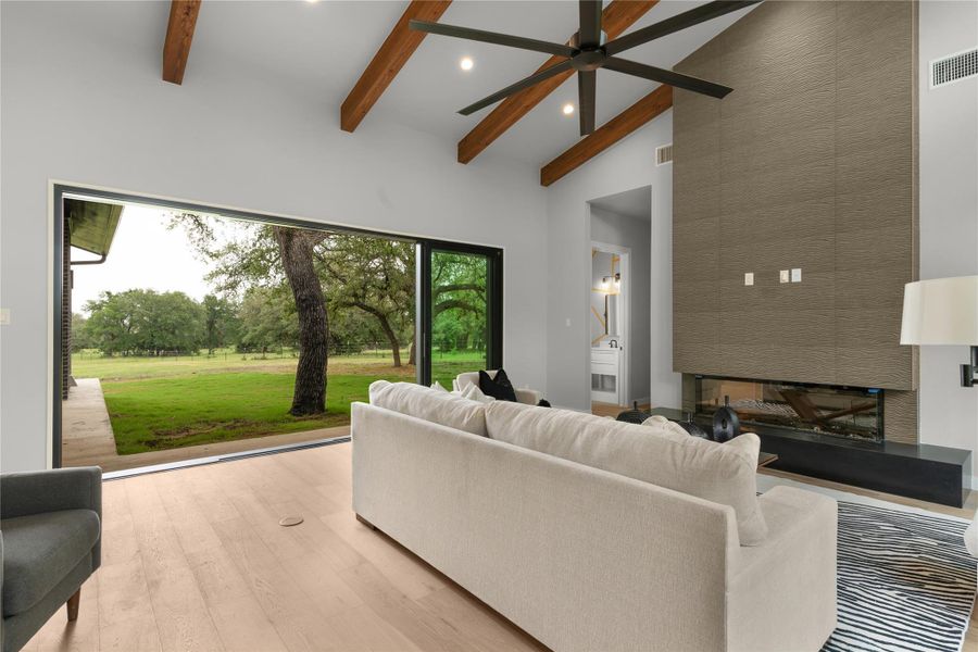 Living area with beam ceiling, high vaulted ceiling, light wood-style flooring, recessed lighting, and a ceiling fan Living area with beam ceiling, high vaulted ceiling, light wood-style flooring, recessed lighting, and a ceiling fan