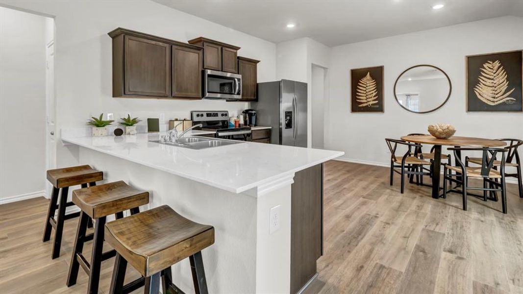 Kitchen with dark wood finish cabinetry, a breakfast bar, light wood-style floors, a peninsula, and recessed lighting Kitchen with dark wood finish cabinetry, a breakfast bar, light wood-style floors, a peninsula, and recessed lighting