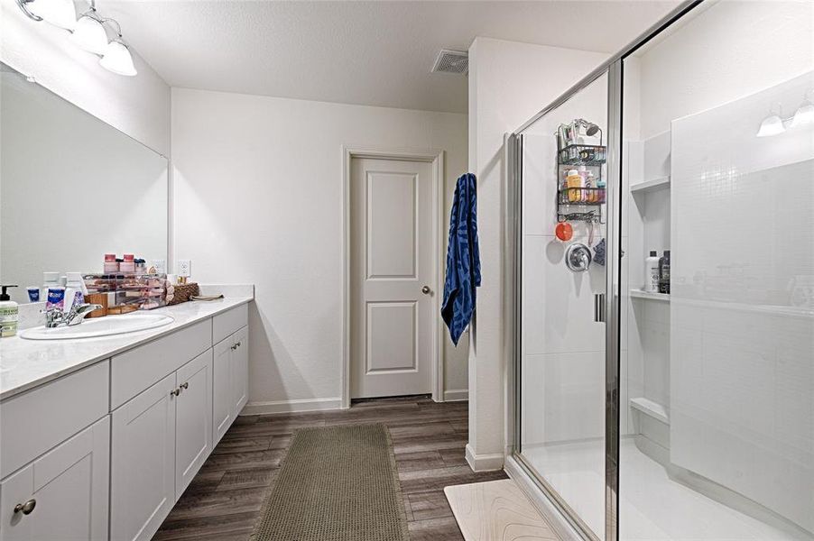 Full bathroom featuring vanity, a stall shower, and dark wood-type flooring Full bathroom featuring vanity, a stall shower, and dark wood-type flooring