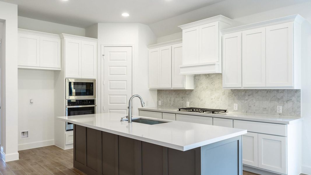 Kitchen featuring backsplash, white cabinets, dark wood-style flooring, a center island with sink, and stainless steel appliances