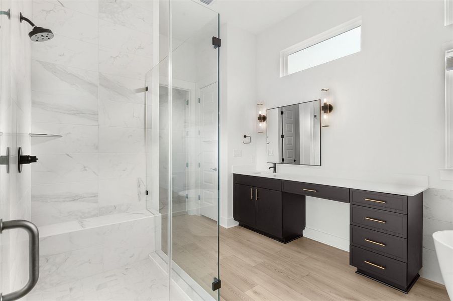 Bathroom with a marble finish shower, vanity, and light wood-type flooring
