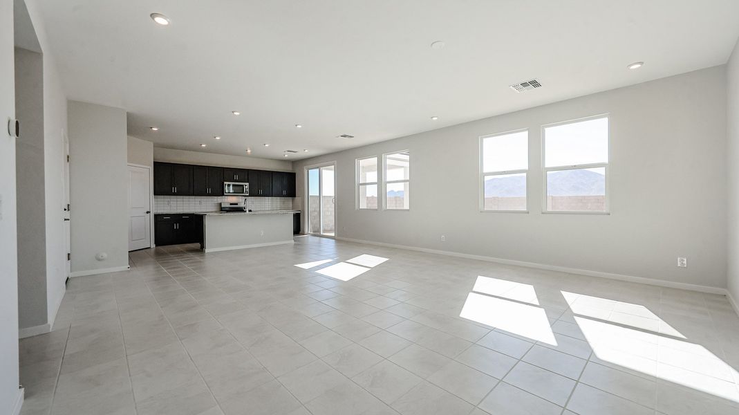 A large empty room with white tile floor and windows.