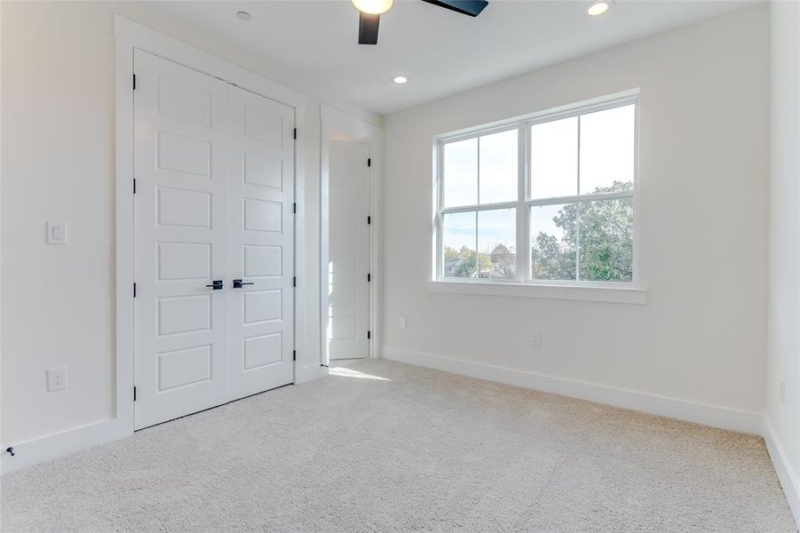 Unfurnished bedroom featuring light carpet and ceiling fan