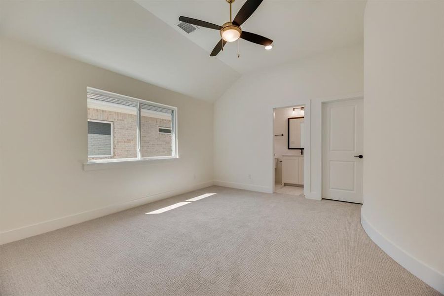 Unfurnished bedroom featuring lofted ceiling, light colored carpet, a ceiling fan, and connected bathroom Unfurnished bedroom featuring lofted ceiling, light colored carpet, a ceiling fan, and connected bathroom