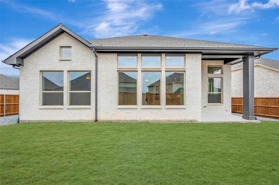 Rear view of house featuring a fenced backyard, brick siding, a patio, and roof with shingles