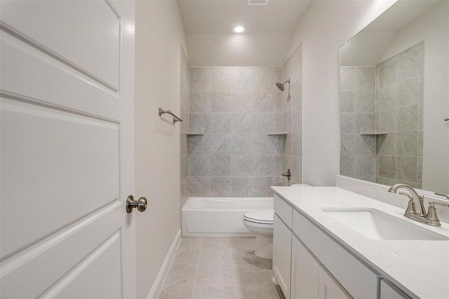 Full bathroom with tiled shower / bath combo, vanity, tile patterned flooring, and toilet