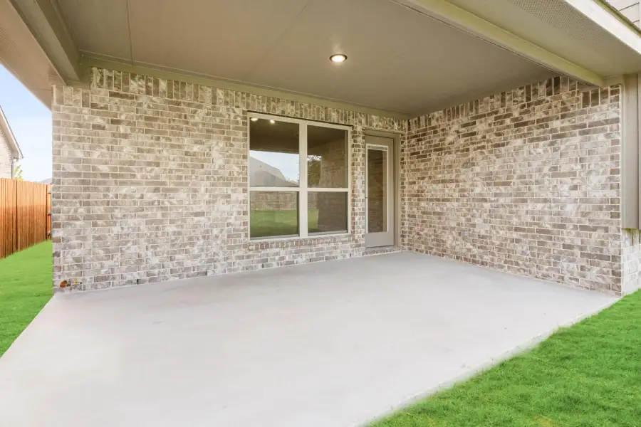 Covered back patio with concrete floor, brick exterior walls, and a single window overlooking the yard