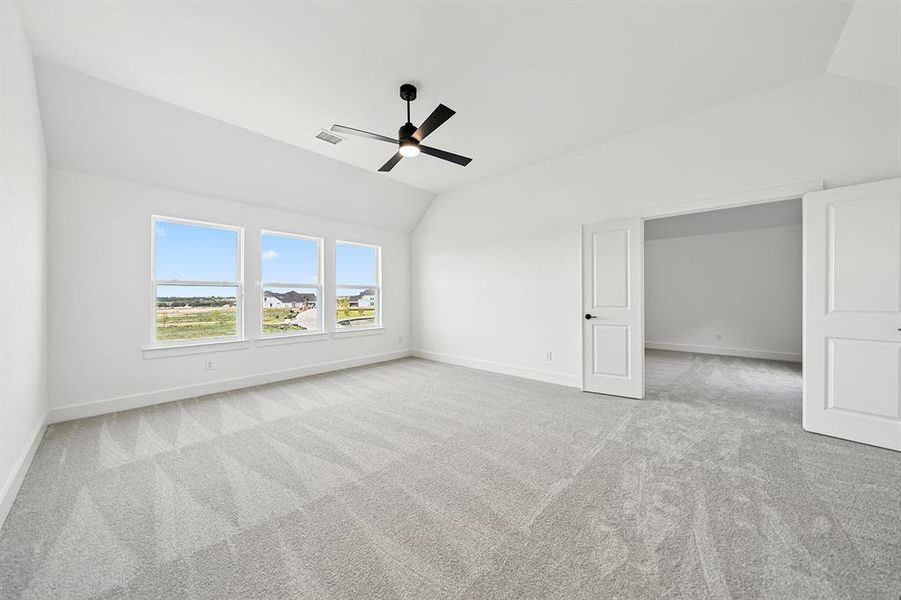 Unfurnished bedroom with vaulted ceiling, light carpet, and a ceiling fan