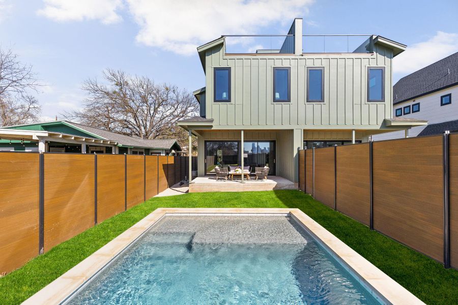 Rear view of house with board and batten siding, a patio, and a fenced backyard