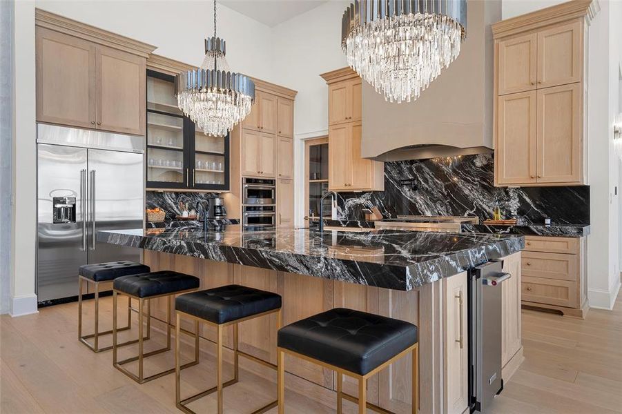 Kitchen featuring light brown cabinets, a breakfast bar area, appliances with stainless steel finishes, backsplash, and light wood-style flooring