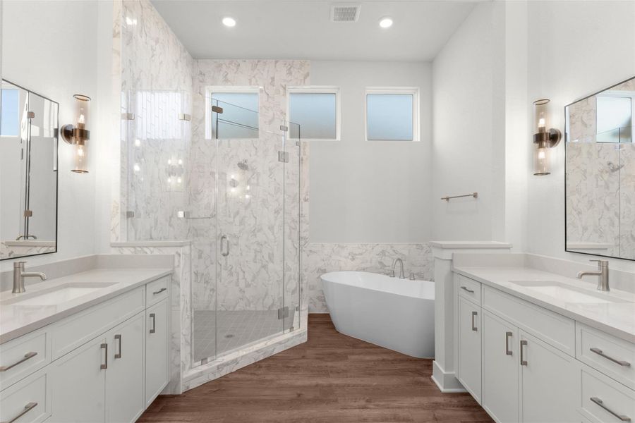 Bathroom featuring two vanities, dark wood finished floors, a freestanding tub, a marble finish shower, and recessed lighting