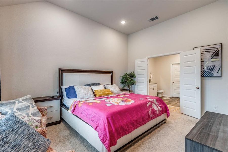 Bedroom with light colored carpet, ensuite bathroom, and recessed lighting