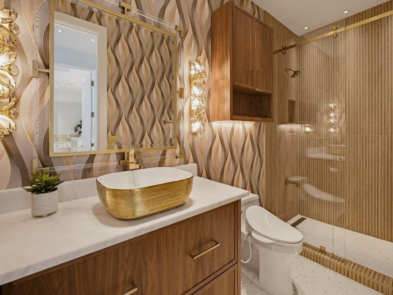 Bathroom featuring a gold vessel sink, wood-finish vanity with gold hardware, and a marble-look countertop