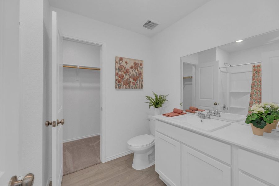 Primary bathroom featuring a spacious walk in closet, vanity, vinyl, and a shower tub combo.