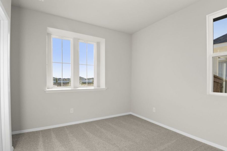 Image of a bedroom with tan carpeting and light grey painted walls and two windows