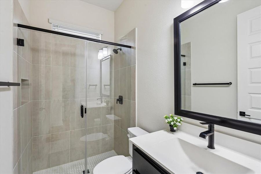 Bathroom with a frameless glass shower enclosure featuring large-format wall tiles and a hexagonal floor tile Bathroom with a frameless glass shower enclosure featuring large-format wall tiles and a hexagonal floor tile