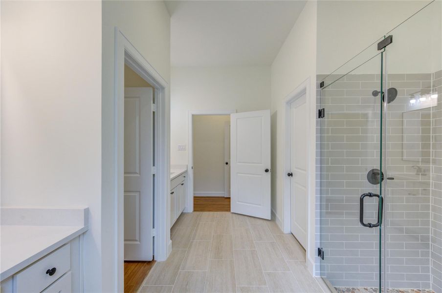 This bathroom offers a bright and elegant space with sleek glass shower doors, modern fixtures, and a blend of crisp white and warm wood tones, creating a soothing, spa-like atmosphere. Double Vanities. This bathroom offers a bright and elegant space with sleek glass shower doors, modern fixtures, and a blend of crisp white and warm wood tones, creating a soothing, spa-like atmosphere. Double Vanities.
