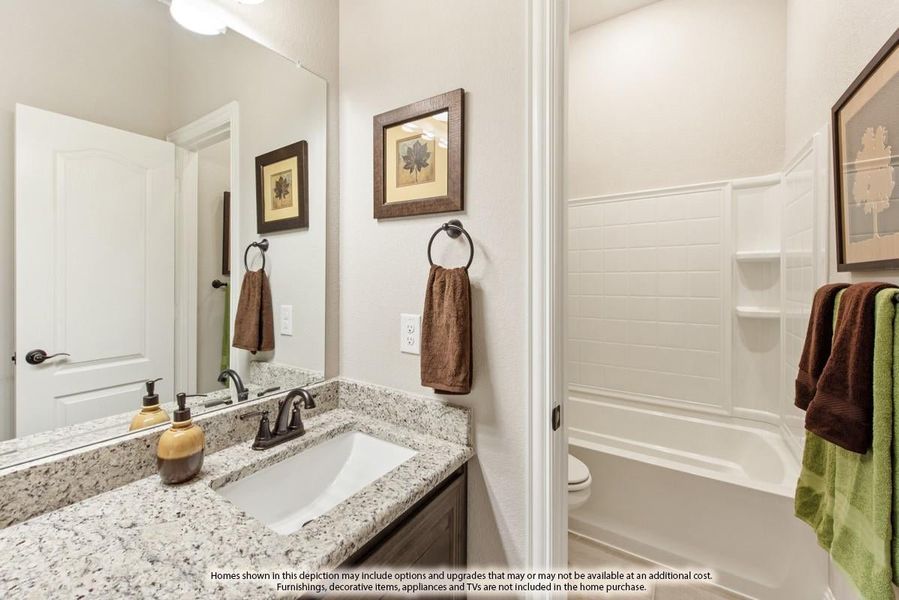 Bathroom with granite countertop vanity, undermount sink, and white tub-shower combo with built-in shelves