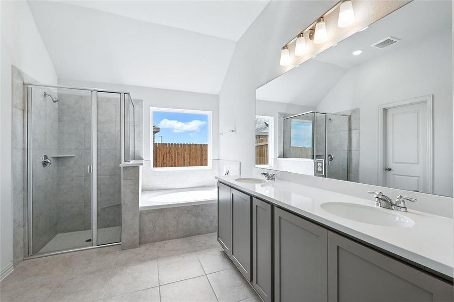 Bathroom featuring lofted ceiling, a bath, a stall shower, double vanity, and light tile patterned floors Bathroom featuring lofted ceiling, a bath, a stall shower, double vanity, and light tile patterned floors
