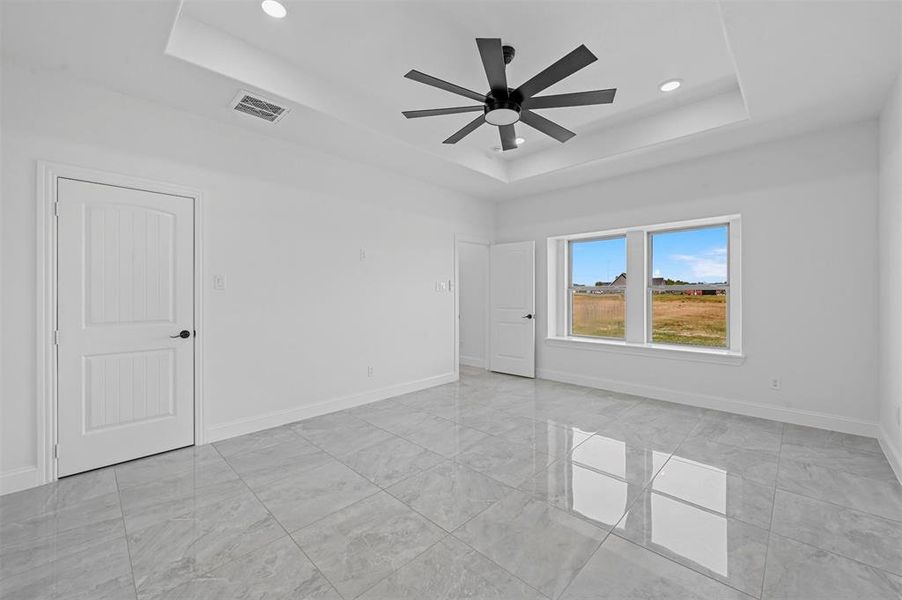 Tiled spare room with a tray ceiling and ceiling fan