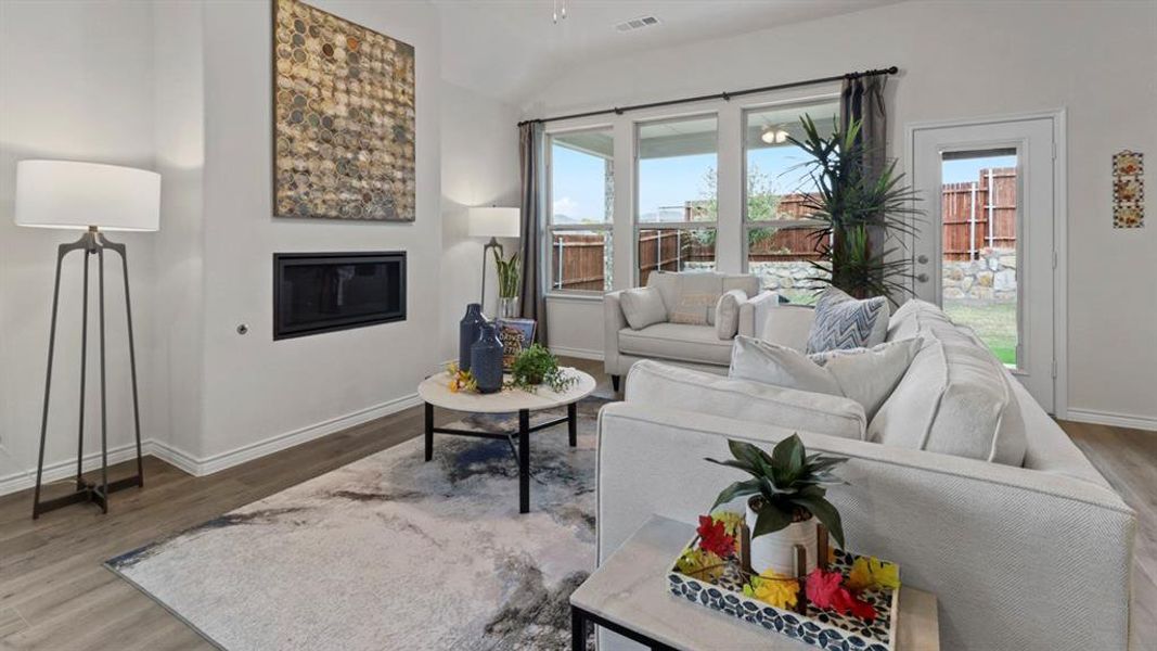 Living room featuring a glass covered fireplace, lofted ceiling, wood finished floors, and plenty of natural light