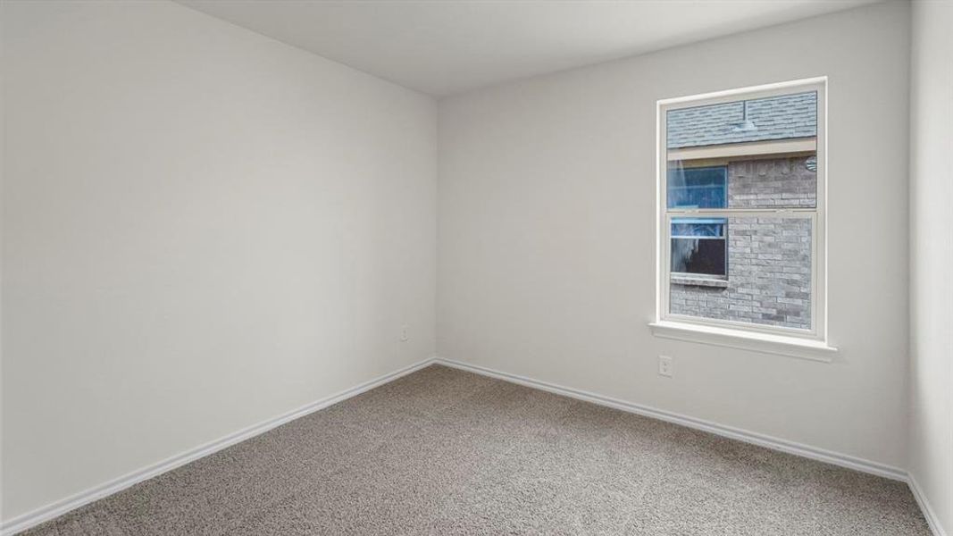 This room features light gray walls, gray carpet, and a window with white trim