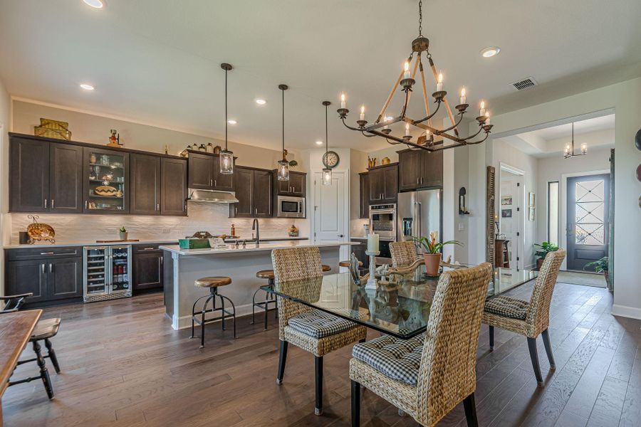 Dining area featuring a chandelier, dark wood finished floors, beverage cooler, recessed lighting, and bar
