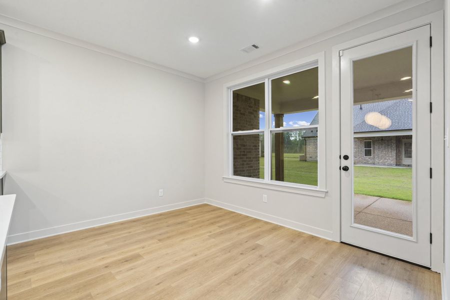 Room featuring light wood-finish flooring, white baseboards, and crown molding Room featuring light wood-finish flooring, white baseboards, and crown molding