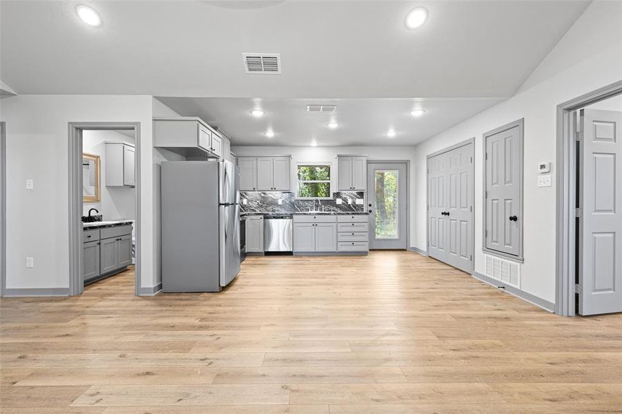 Kitchen with gray cabinetry, stainless steel appliances, recessed lighting, decorative backsplash, and light wood-type flooring Kitchen with gray cabinetry, stainless steel appliances, recessed lighting, decorative backsplash, and light wood-type flooring
