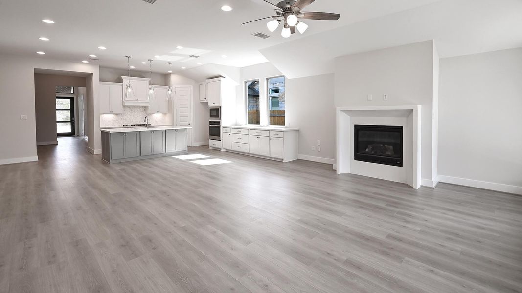 Unfurnished living room with light wood finished floors, a ceiling fan, recessed lighting, and a glass covered fireplace Unfurnished living room with light wood finished floors, a ceiling fan, recessed lighting, and a glass covered fireplace