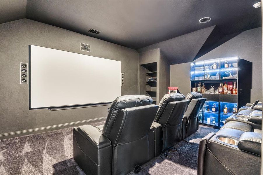 Carpeted home theater room with baseboards and a textured wall