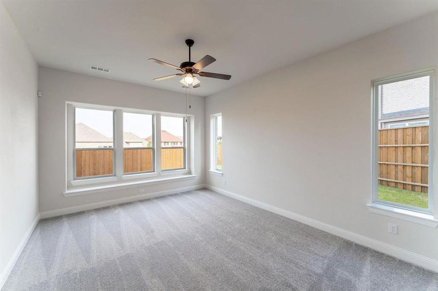 Carpeted empty room with a healthy amount of sunlight and ceiling fan